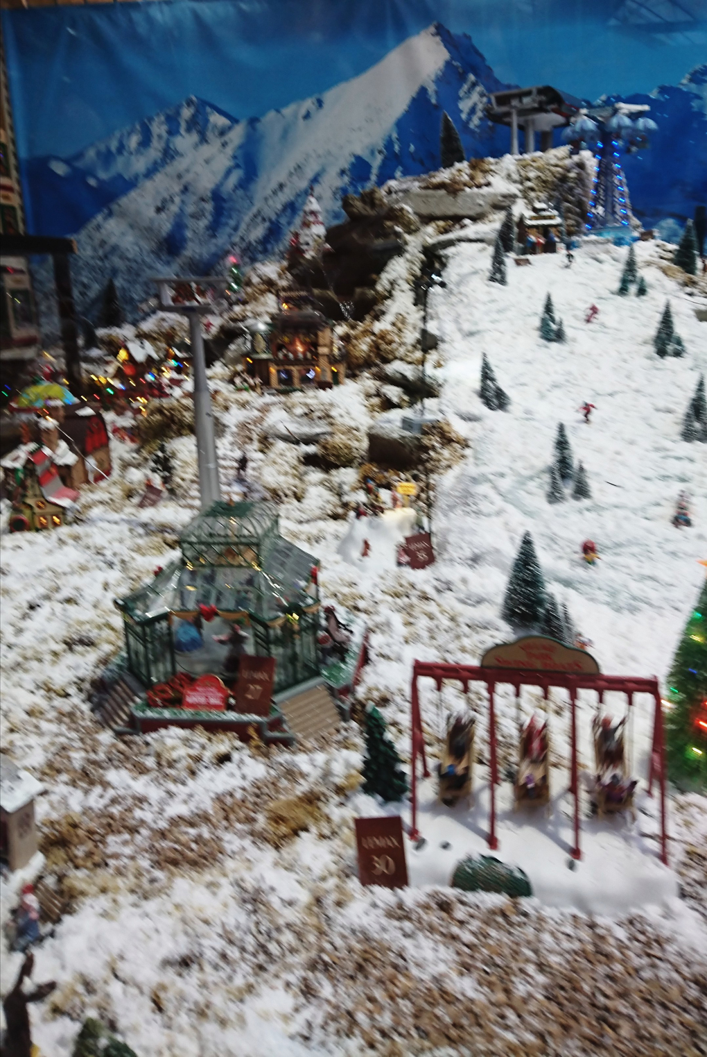 A wintry scene featured on the side of a mountain in minature depicting a village, cable cars, swing boats, a frozen lake, merry go rounds and skiers - brilliant!