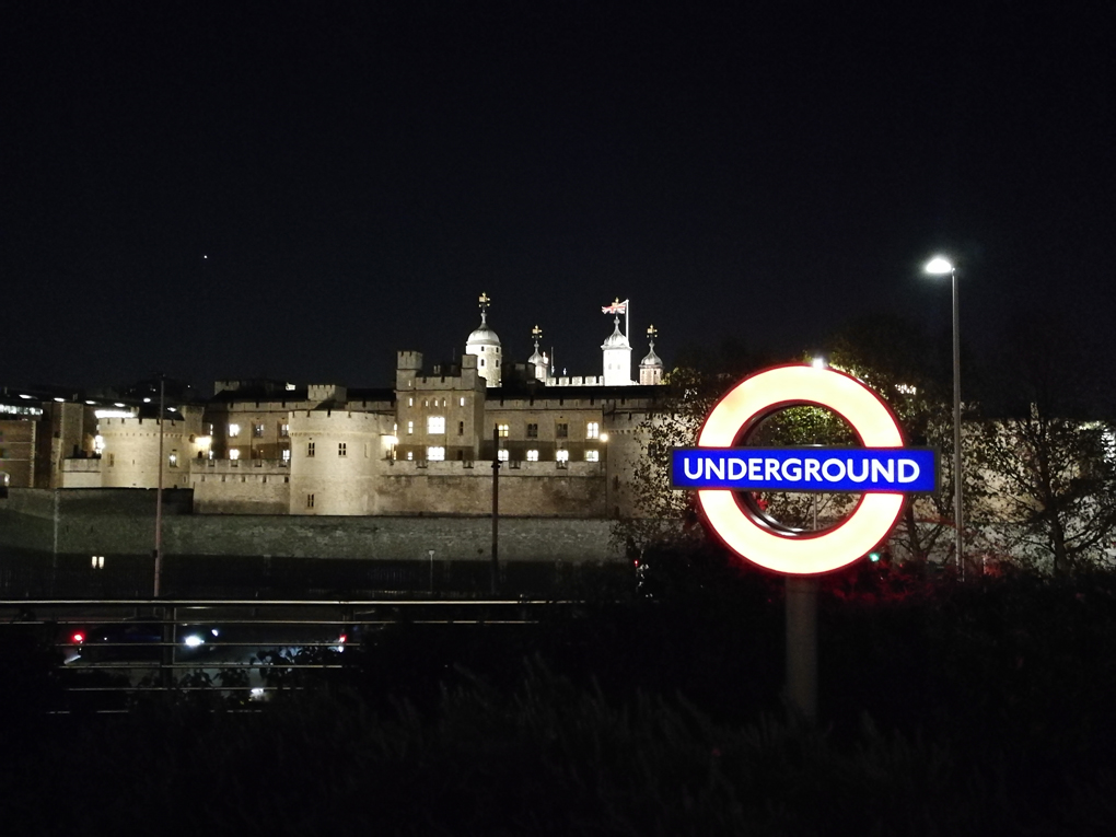 night shot of the Tower of London with a lit underground sign in the foreground