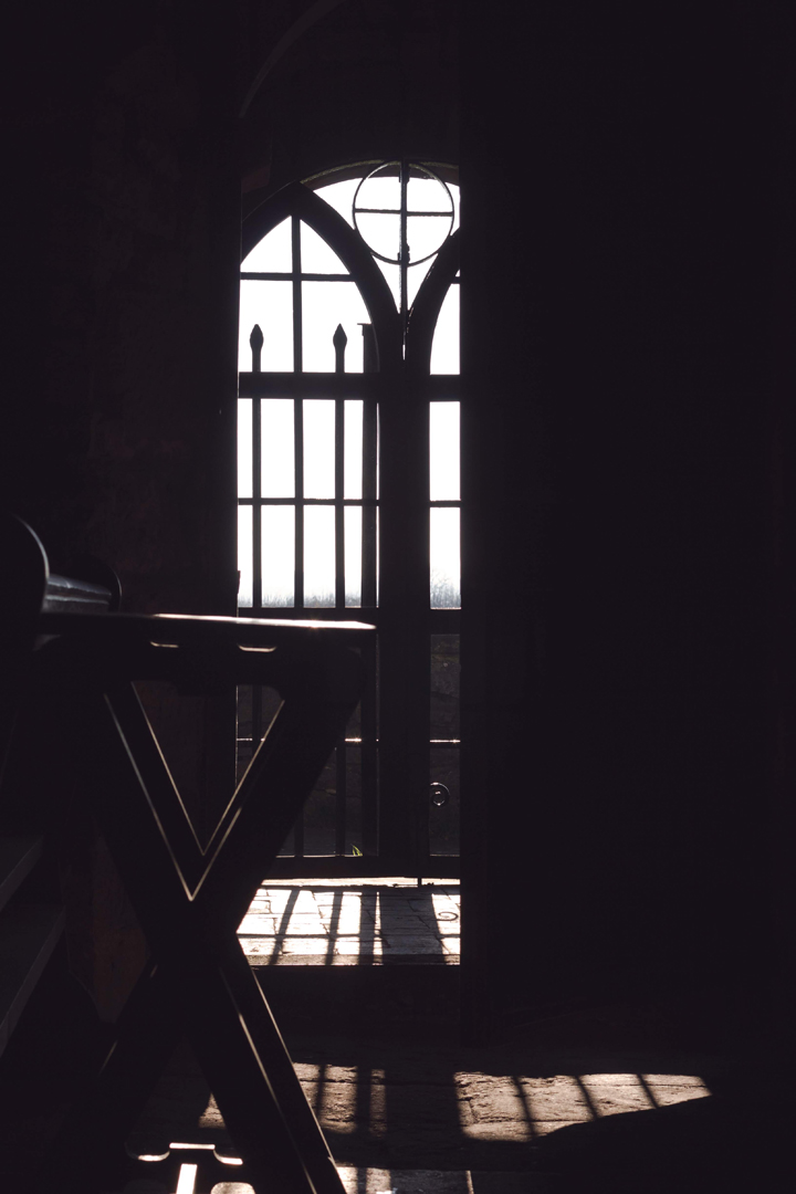 Old door of beautiful medieval church silhouetted against the low wintry light.