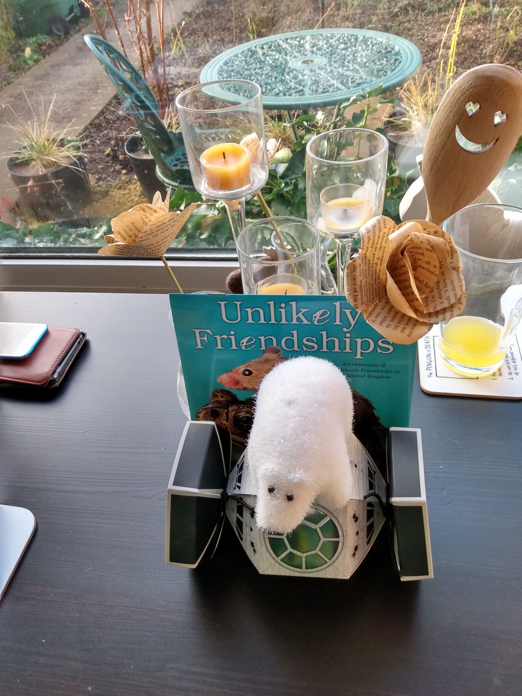 A small, decorative polar bear sits atop a cardboard spaceship with a calendar titled 'unlikely friends' sat behind it.