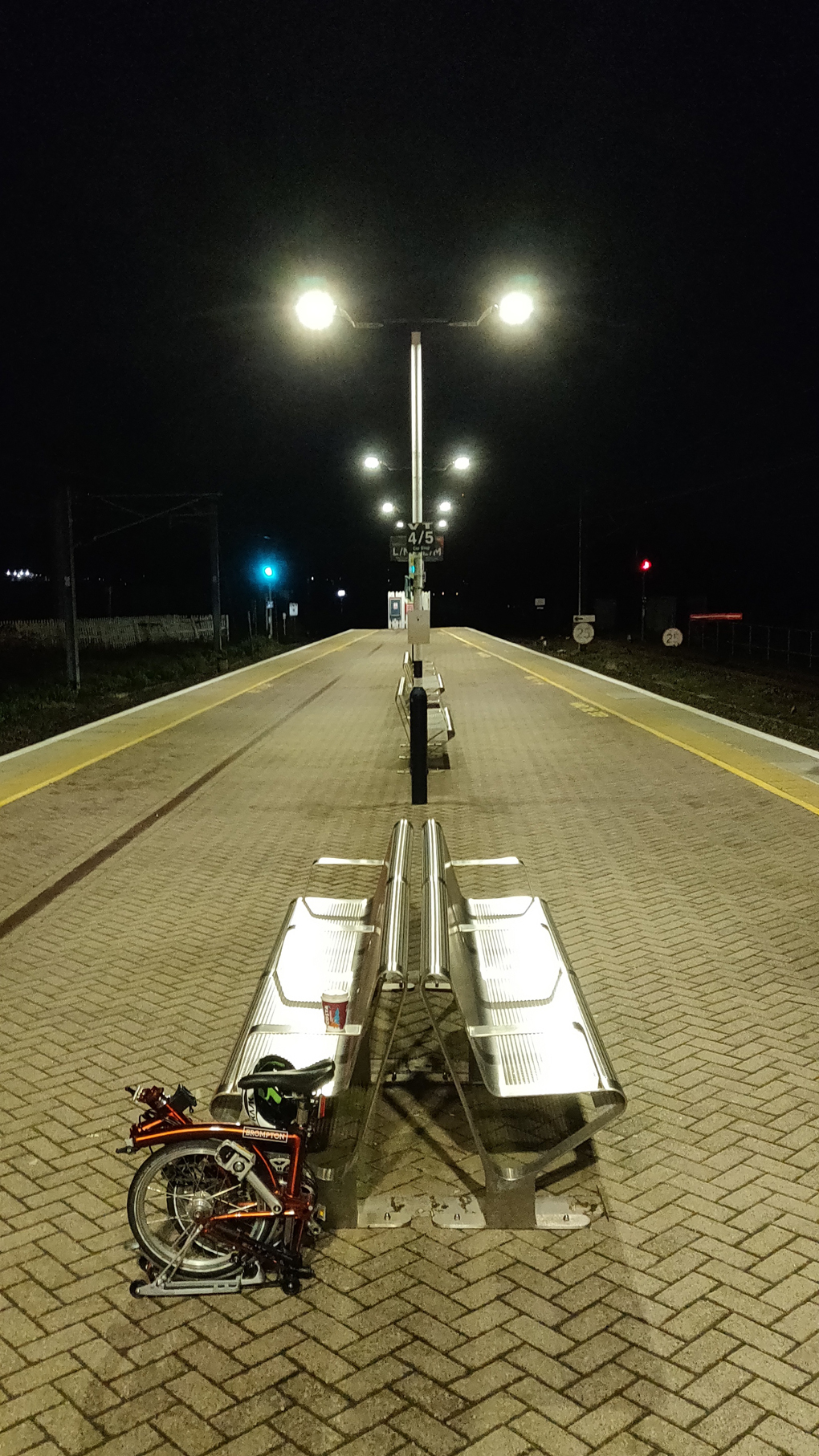 On an empty train station platform in the evening with a Brompton folded up, waiting for the big train to London for the last week of work this year.