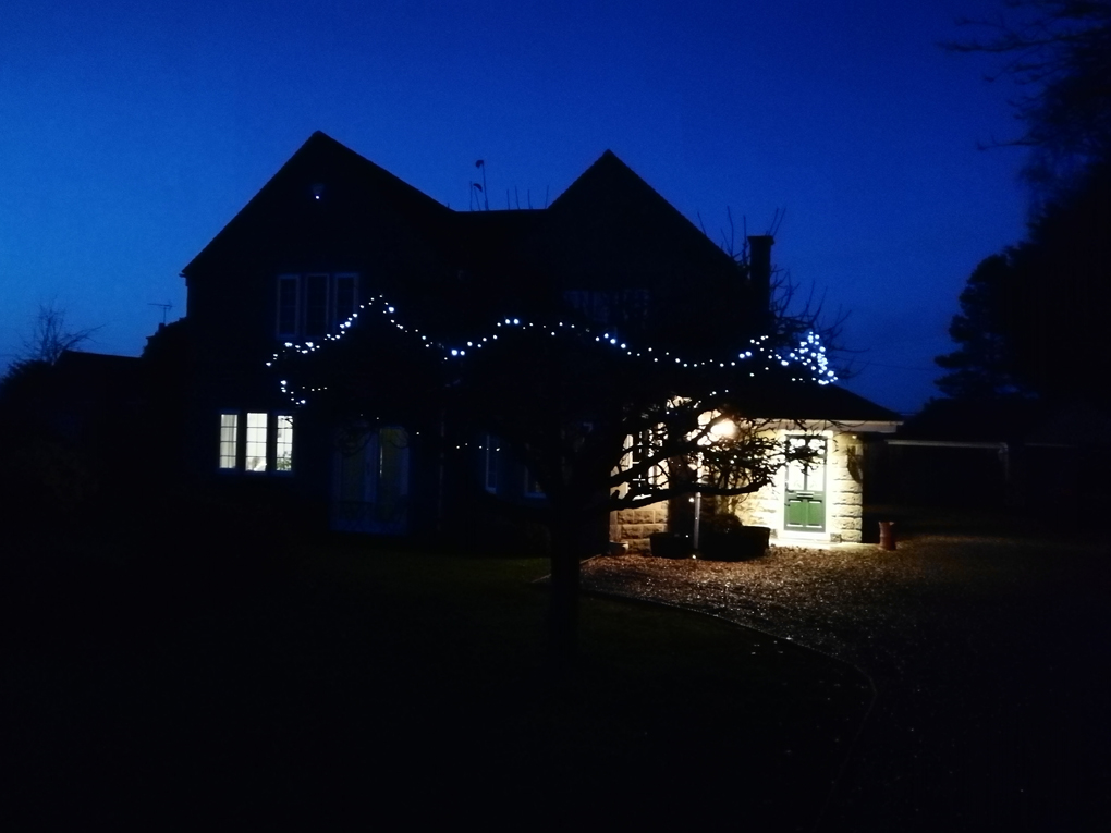 house in the darkness with a few lights on and some Christmas lights