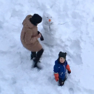 Aerial view of an adult and a child building a snowman