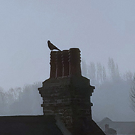 The sun behind misty cloud rises over terraced rooftops.