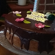 Table in front of fireplace with cakes on top, including birthday cake with unlit firework type candle