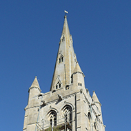 Workmen on scaffolding high up church tower