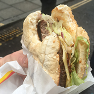 A hand holding a burger with a piece bitten off.