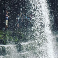 A large waterfall, with people standing behind it