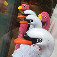 The handles of several umbrellas, shaped like swans and flamingos.