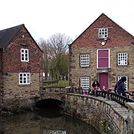 This picture shows a mill house and willow tree which are beautifully reflected in a pond