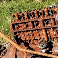 Rusted car on a slope between road and loch in the Outer Hebrides.