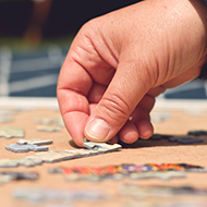 Hand placing puzzle pieces.