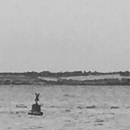 A rocky beach with a groyne, the sea, and more land in the far distance