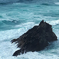 Towering, rough pillars of dark stone standing high above stormy waves
