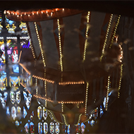 The reflection of a helter skelter in the water of a baptismal font with coins in the bottom.