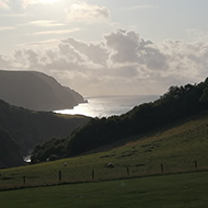 view of the sea between hills with the sun going down