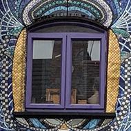 A house completely covered in colourful mosaic tiles.