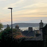 A view down a winding road. In the background is a multi-coloured pastel sky.