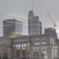 Reflections of bright post-it notes and whiteboards inside the building contrast with the dramatic grey London buildings outside.