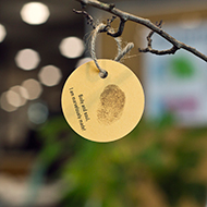 Close up of a paper leaf, with a thumbprint and a quote reading, 