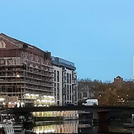 Looking along a very still river in the middle of a busy city in late sunrise light