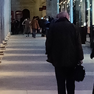 People walking in the brightly lit colonnade outside the Royal Opera House late at night