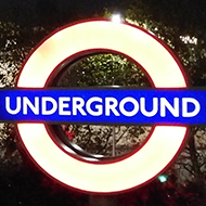 night shot of the Tower of London with a lit underground sign in the foreground