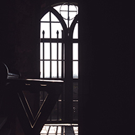 Old door of beautiful medieval church silhouetted against the low wintry light.