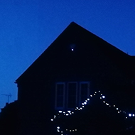 house in the darkness with a few lights on and some Christmas lights