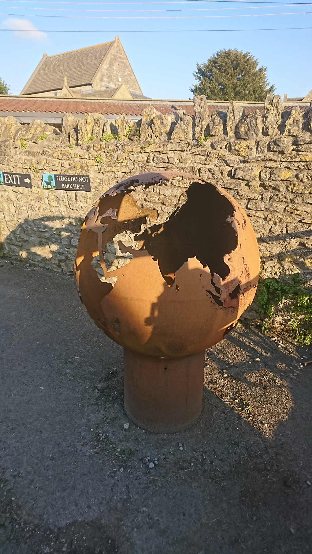 A rusty old globe of metal approx 3 1/2ft in diameter, set on a smaller cylindrical tube of the same. The map of the world had been cleverly cut out in the surface of the globe, the rust illuminated in the sunlight. Cool concept for a sculpture!