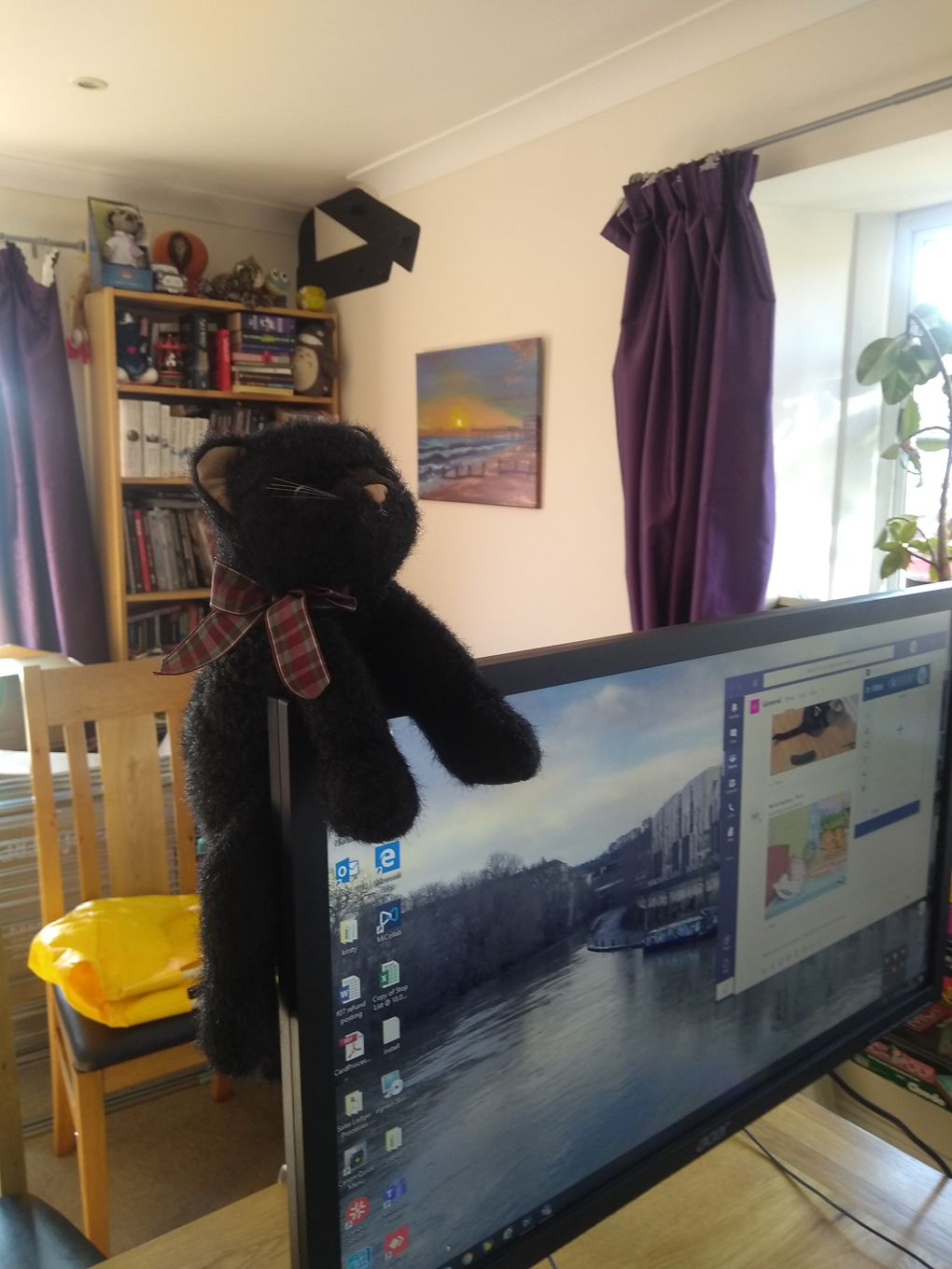 Computer screen with toy cat perched on top in living room