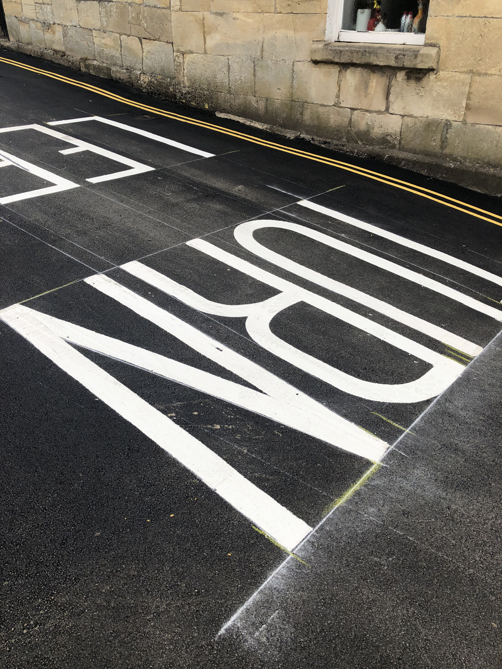 The words 'Turn left' painted in large white letters on a black road