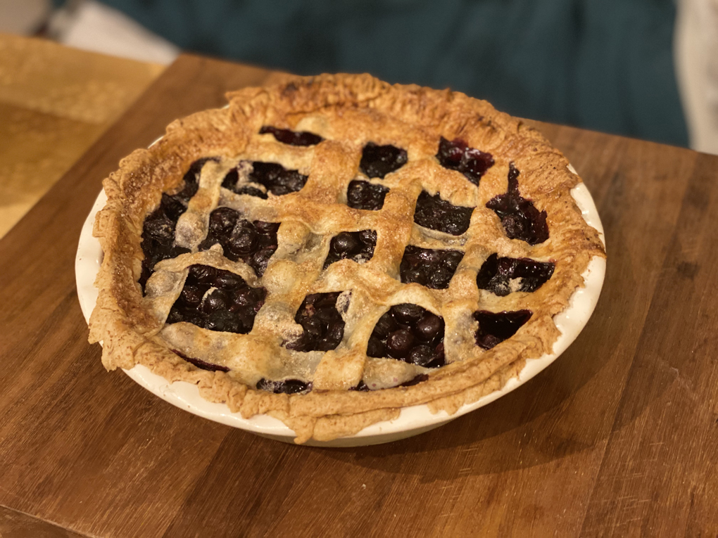 A blueberry pie looking pretty damn amazing except for some ragged edges on the crust where it kind of looks like a critter trying to escape being devoured by a slime monster