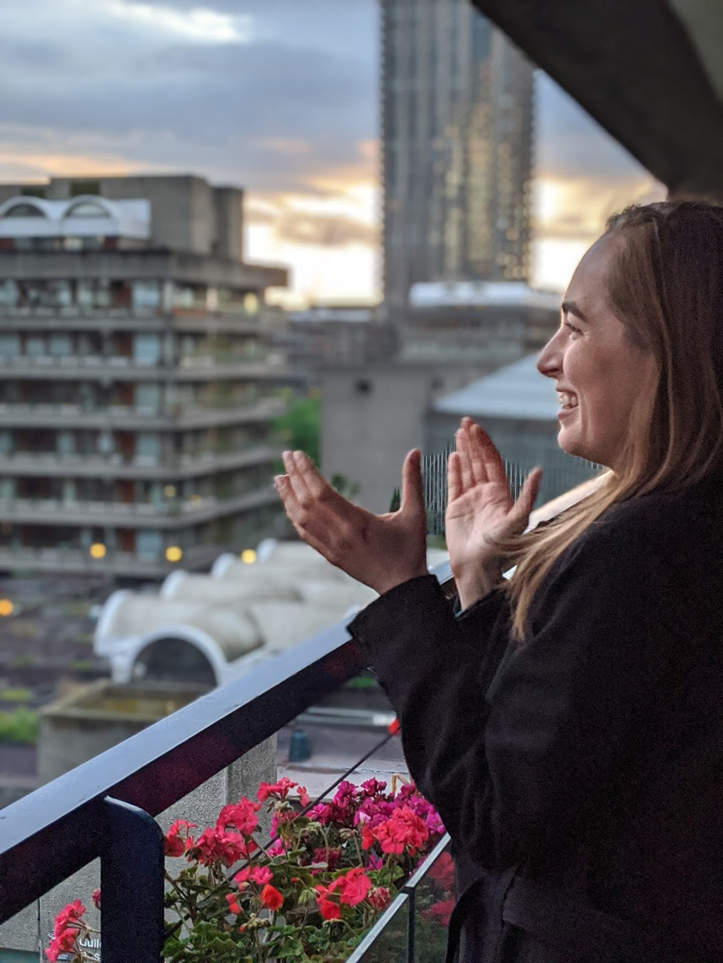 Woman clapping from balcony surrounded by flowers