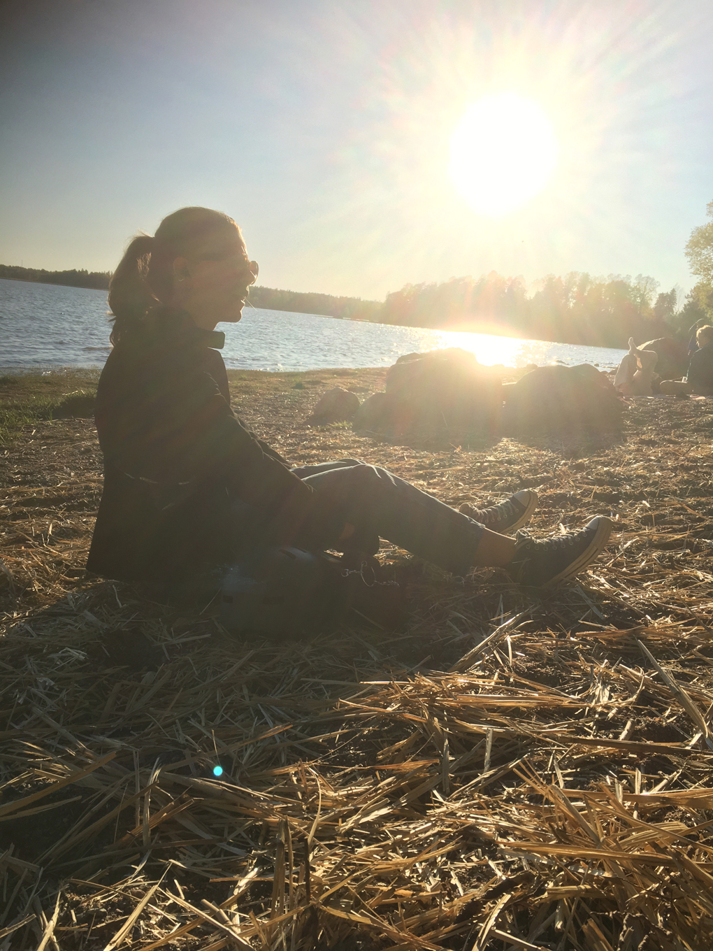 Woman sitting on a beach in the sunset.