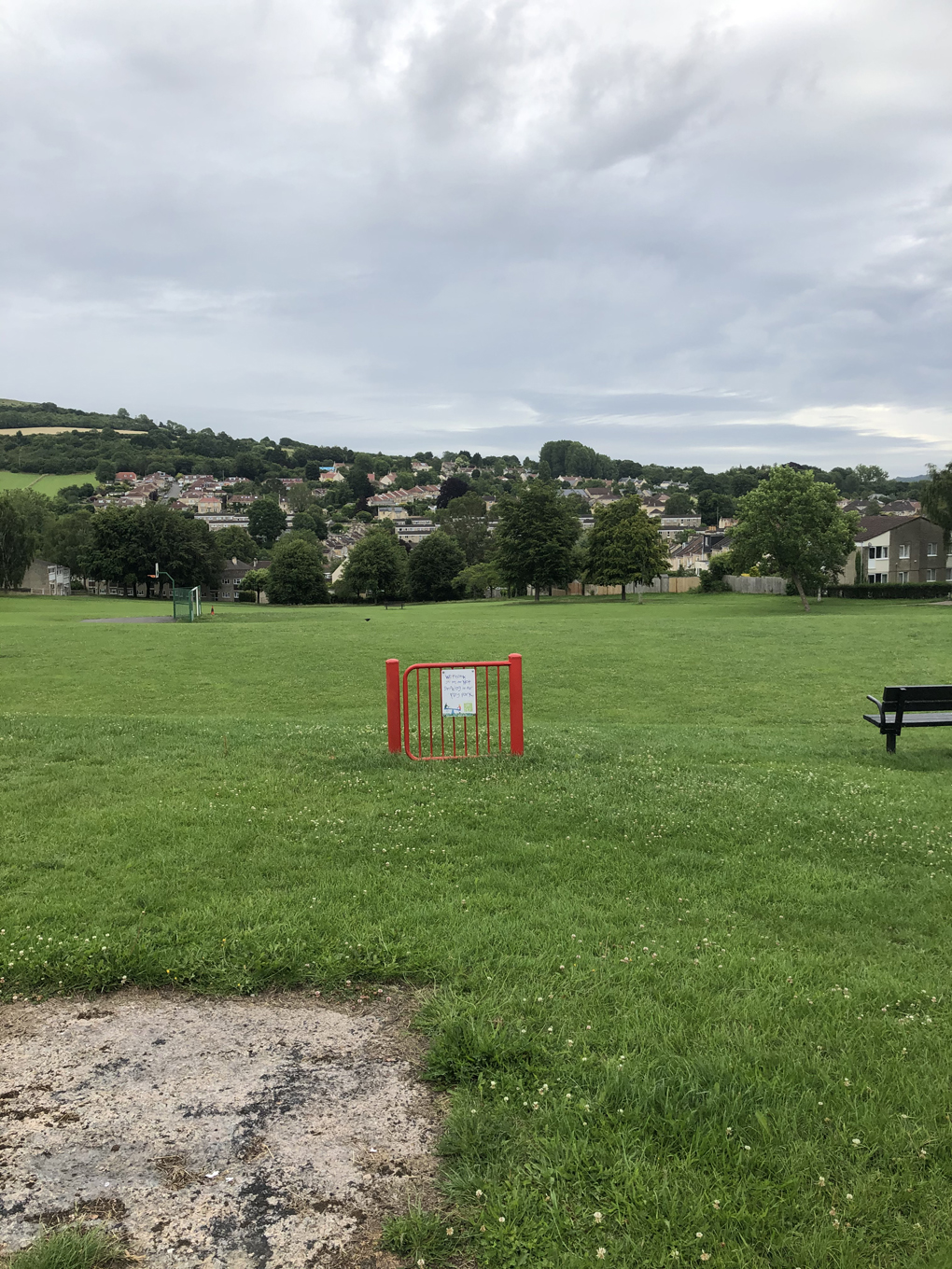 A red metal gate standing in the middle of a green field