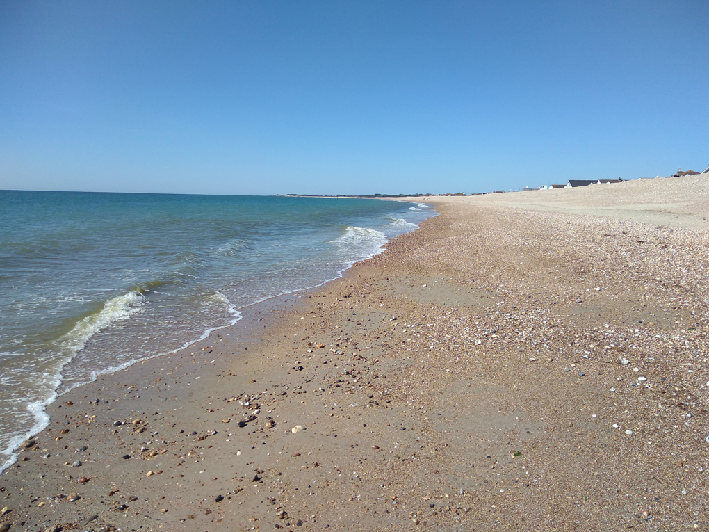 A big stretch of a completely empty beach under a blue sky