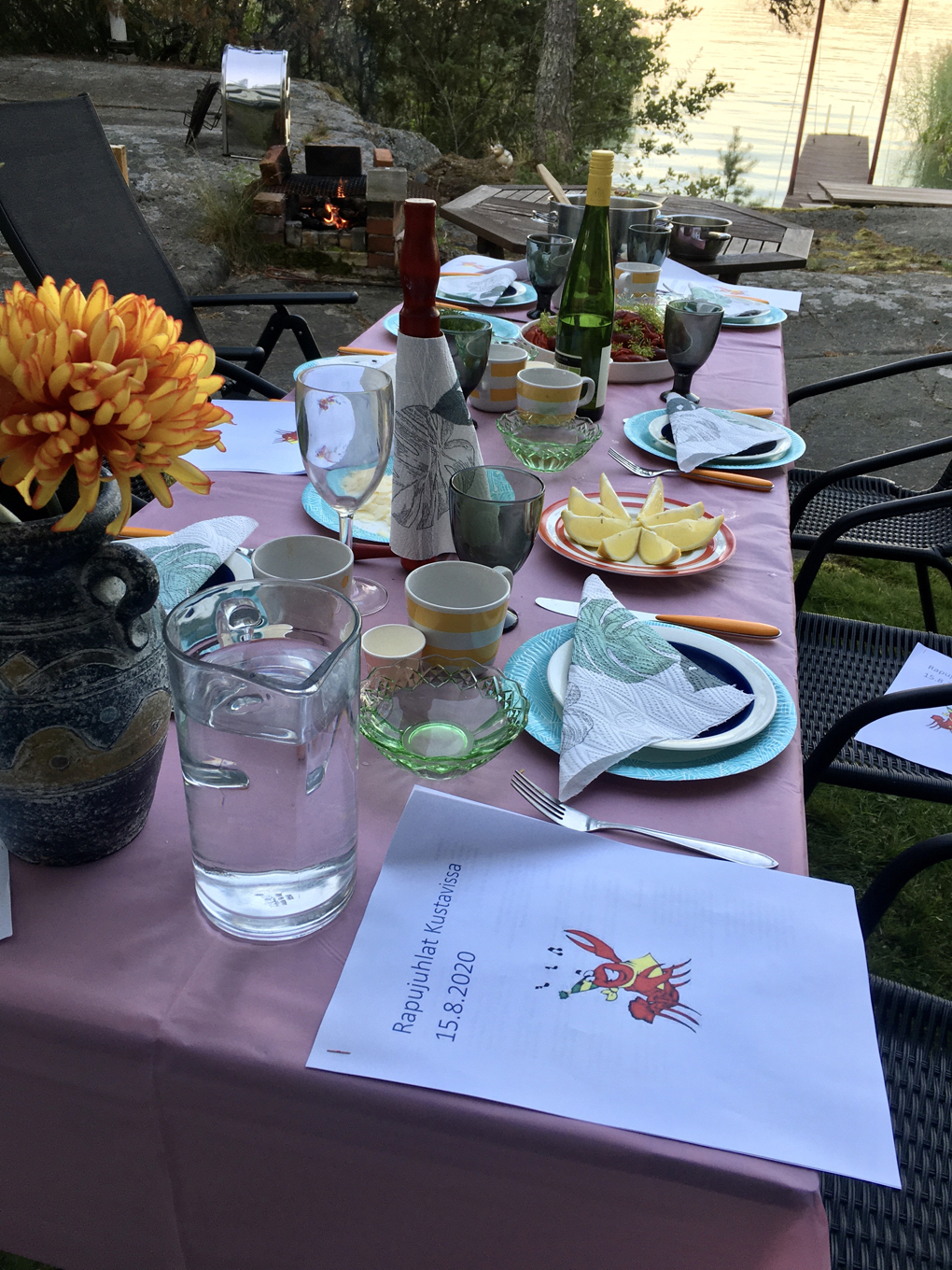 Dinner table set outside by water.