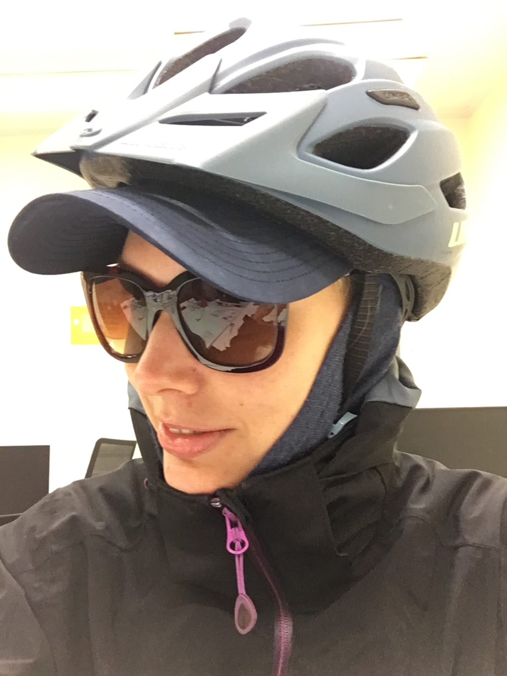 Woman wearing a cycling helmet, cap and sunglasses.