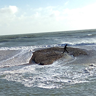 This picture shows the waves crashing over the shingle wall of a lagoon