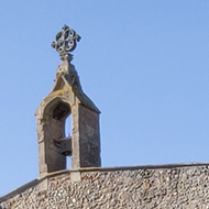 A small boy wandering in the sunny churchyard of a medieval flint and stone built church