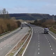 View of an English motorway banked by green hills on either side, with almost no traffic using it during the British COVID-19 lockdown in late March 2020
