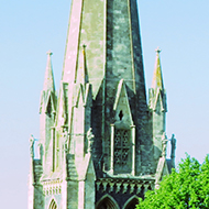 The spire of St Martin's church Dorking  is framed by rooftops on a sunny lock-down day.