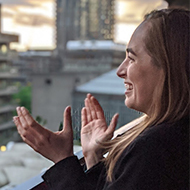 Woman clapping from balcony surrounded by flowers