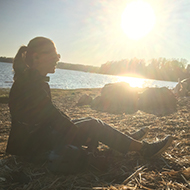 Woman sitting on a beach in the sunset.