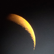 A hazy crescent moon viewed through a telescope