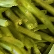 Chopped onions and parsley sizzling in a pot and prepared runner beans waiting on the side to join them.