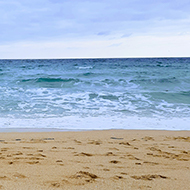 Horizontal bands of yellow sand, crashing waves, blue seas, and a vibrant blue sky