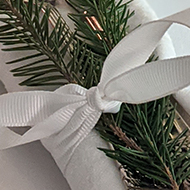 Cutlery wrapped in napkin with festive foliage, blurred platter of turkey in background