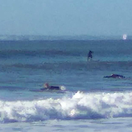 Rough sea and blue sky with some surfers  riding the waves